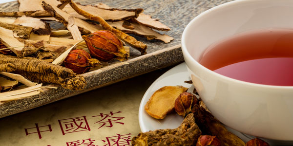 Eine Tasse Tee vor getrockneten, chinesischen Kräutern