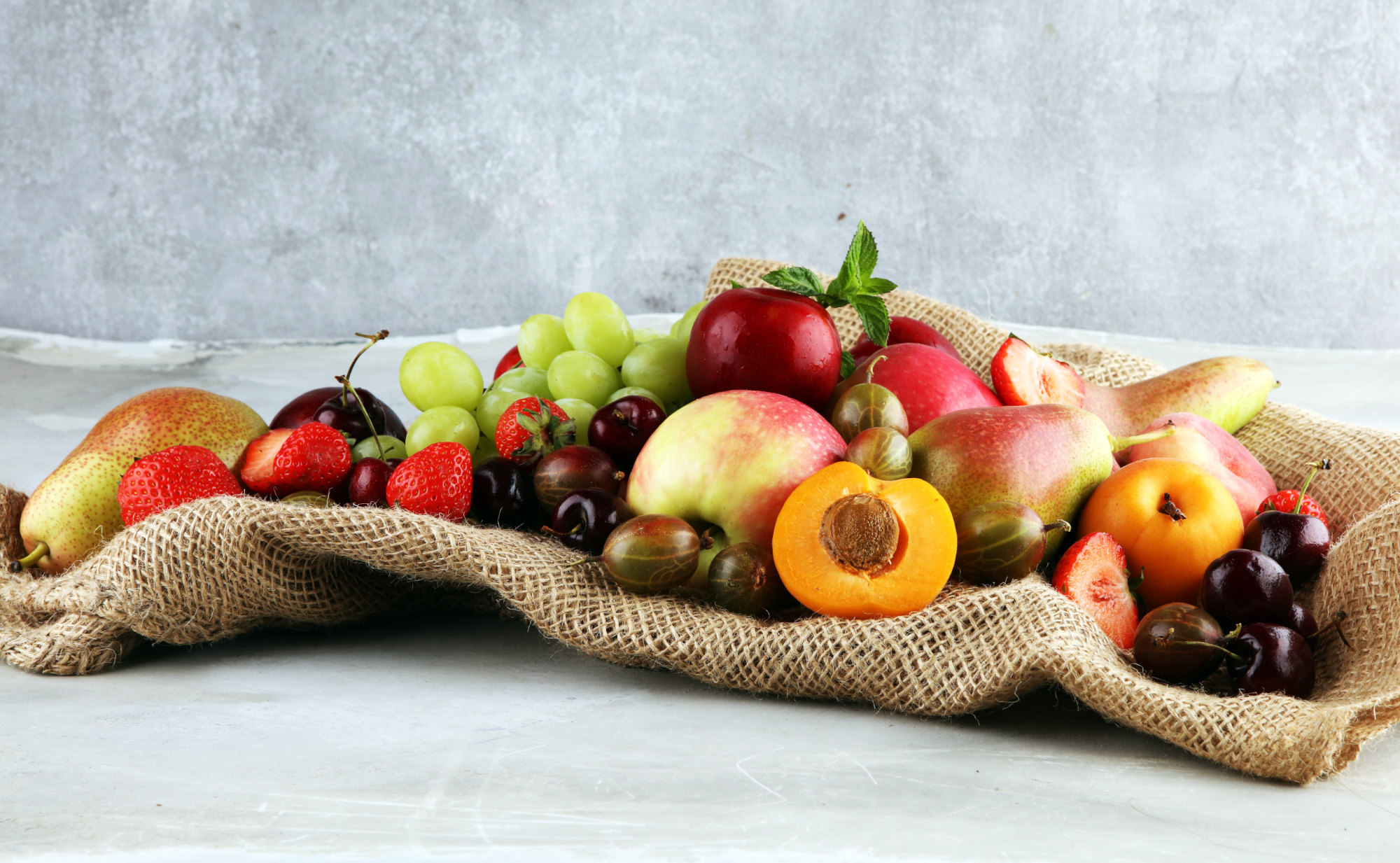 Ein Arrangement aus frischen, farbenfrohen Früchte wie Erdbeeren, Kirschen, Birnen, Äpfel, Aprikosen und Stachelbeeren, das symbolisch für die Kraft der Antioxidantien in Pflanzen steht.